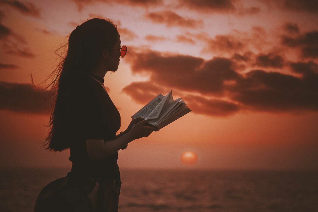 VeneziaOrientale@news: una giovane donna con un libro aperto davanti al mare